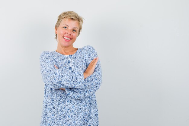 Beautiful woman standing with crossed arms in patterned blouse and looking cheery. front view. space for text