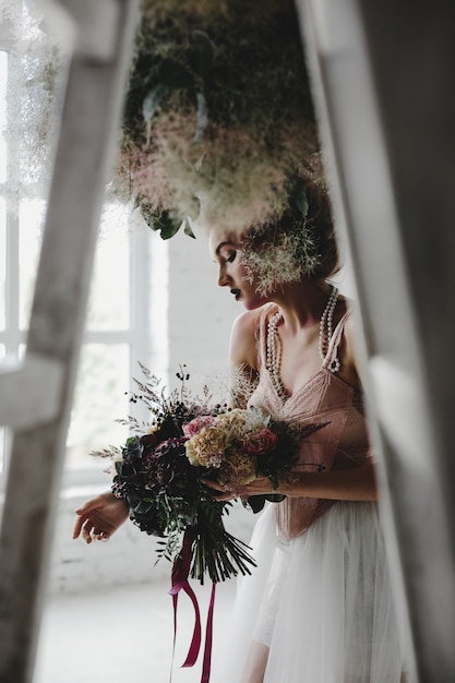 Beautiful woman stands with a bouquet among hanging laundry in the room