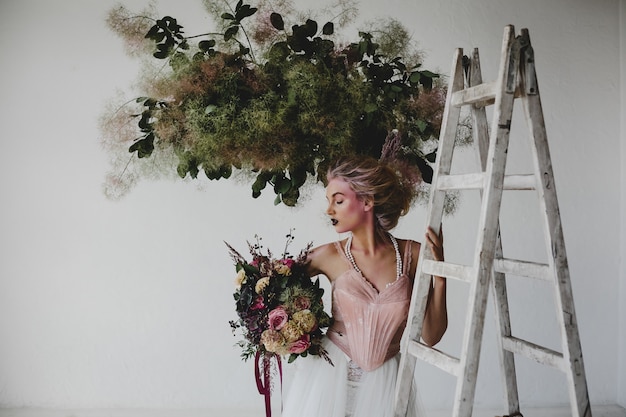 Beautiful woman stands with a bouquet among hanging laundry in the room