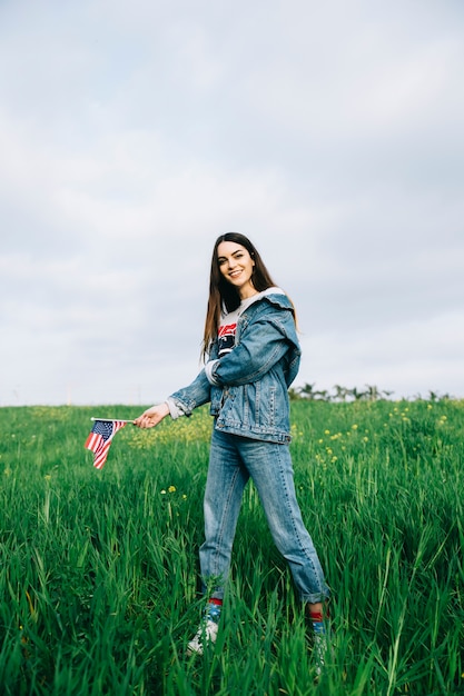 Free photo beautiful woman staying in casual clothes on grass with small flag