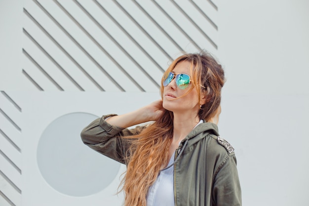 Beautiful woman in sunglasses standing outside during daytime .