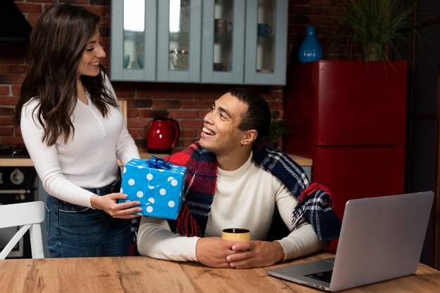 Beautiful woman surprising man with a gift