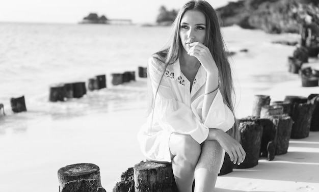 Beautiful woman in swim wear sitting by the ocean