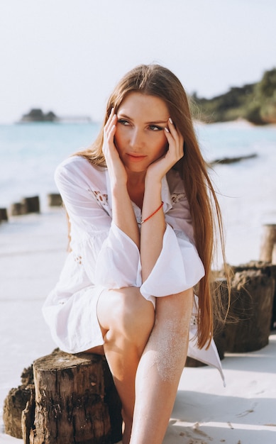 Free photo beautiful woman in swim wear sitting by the ocean