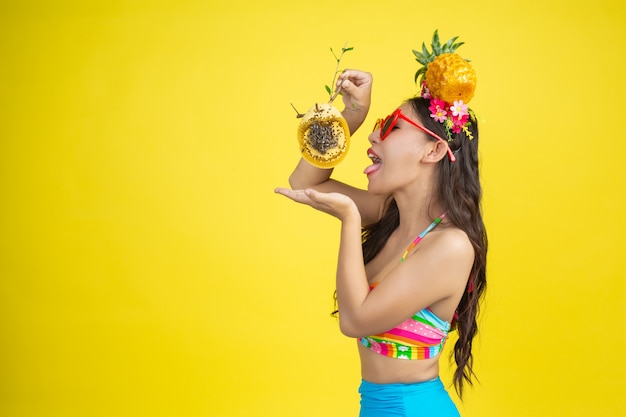 Beautiful woman in a swimsuit carrying a honeycomb poses on yellow