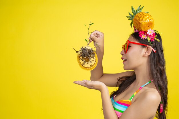 Beautiful woman in a swimsuit carrying a honeycomb poses on yellow