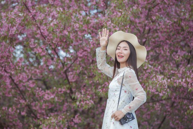 A beautiful woman takes a picture with a film camera in the Sakura flower garden.