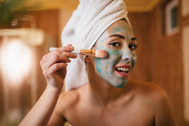 Beautiful woman taking care of her skin and applying facial mask