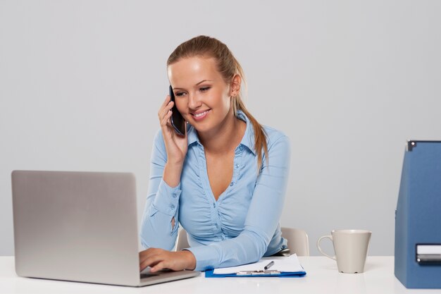 Красивая женщина разговаривает по мобильному телефону во время работы в офисе