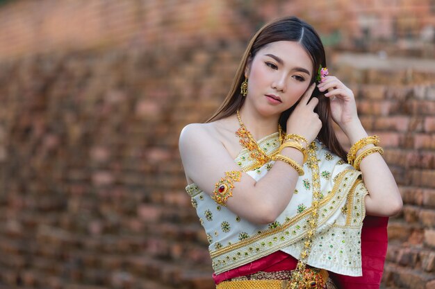 Beautiful woman in thai traditional outfit smiling and standing at temple