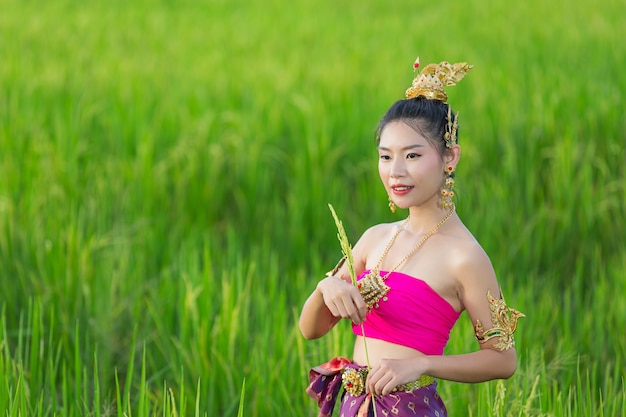 笑顔で寺院に立っているタイの伝統的な衣装の美しい女性