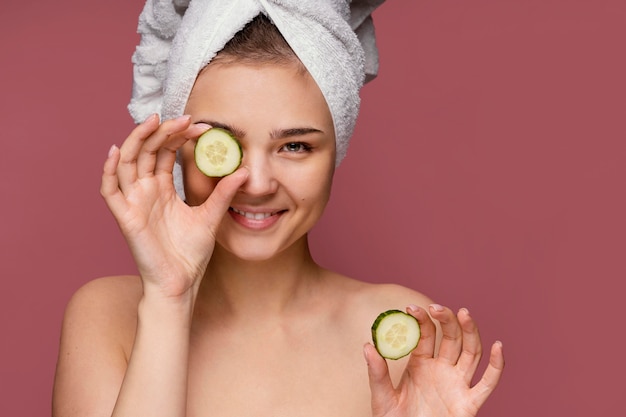 Beautiful woman using cucumber slices for eyes