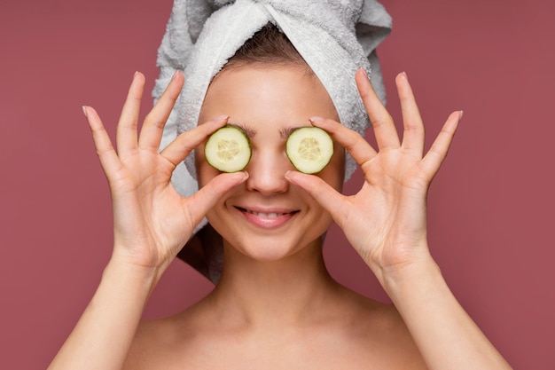 Free photo beautiful woman using cucumber slices for eyes