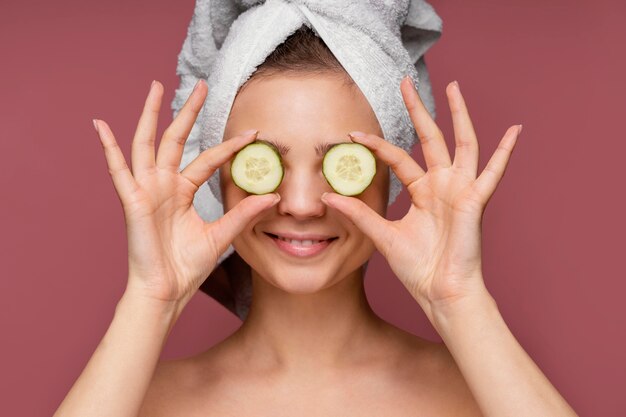 Beautiful woman using cucumber slices for eyes