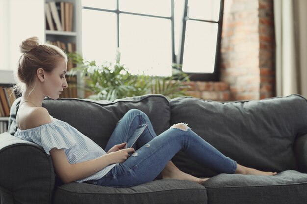 Bella donna con tavoletta digitale, sdraiato sul divano