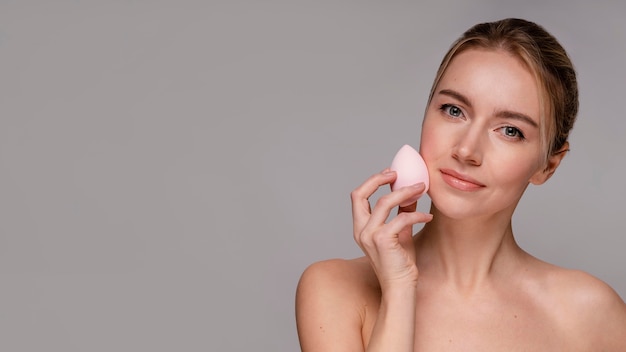 Bella donna che utilizza un frullatore per il trucco