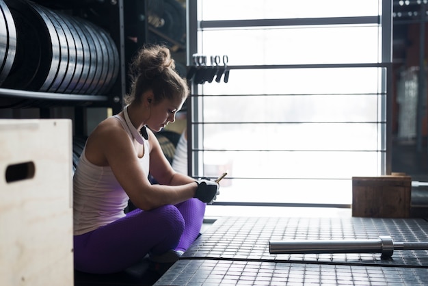 Beautiful woman using smartphone in gym 