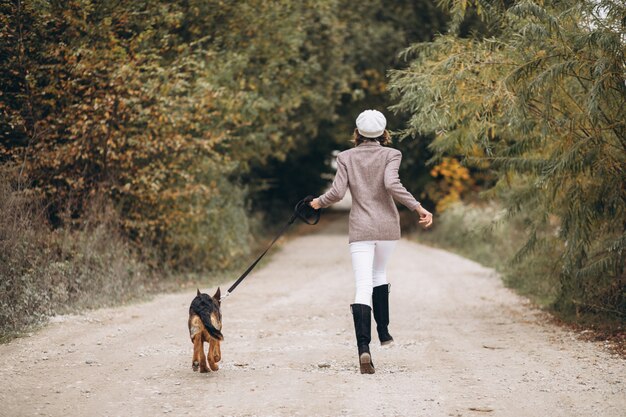 Красивая женщина выходя ее собака в парке осени