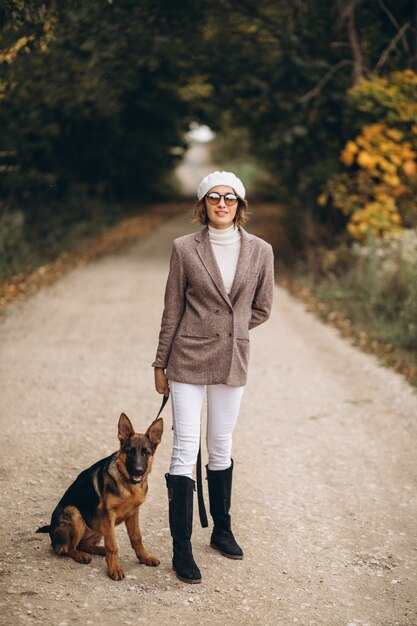 秋の公園で彼女の犬を歩いて美しい女性