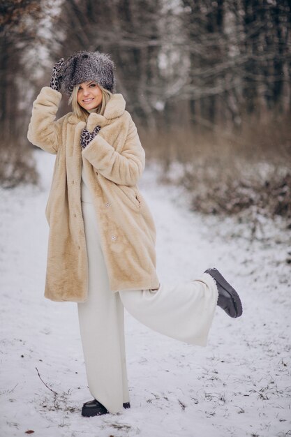 Красивая женщина гуляет в парке, полном снега