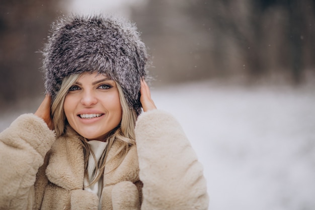 Bella donna che cammina nel parco pieno di neve