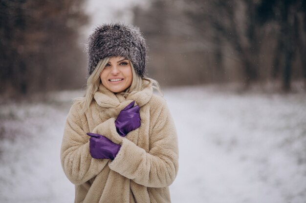 Beautiful woman walking in park full of snow