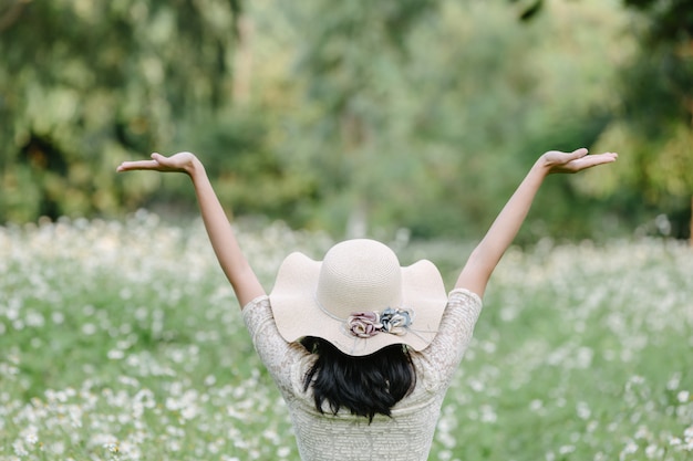 Beautiful woman wearing a cute white dress, standing in a field of flowers