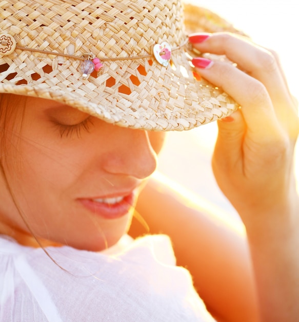 Foto gratuita bella donna che indossa un cappello nella luce del tramonto