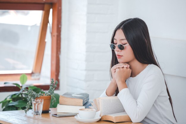 コーヒーショップに座っている長袖の白いシャツを着ている美しい女性