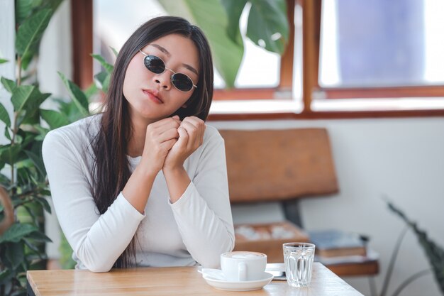 A beautiful woman wearing a long-sleeved white shirt sitting at a coffee shop