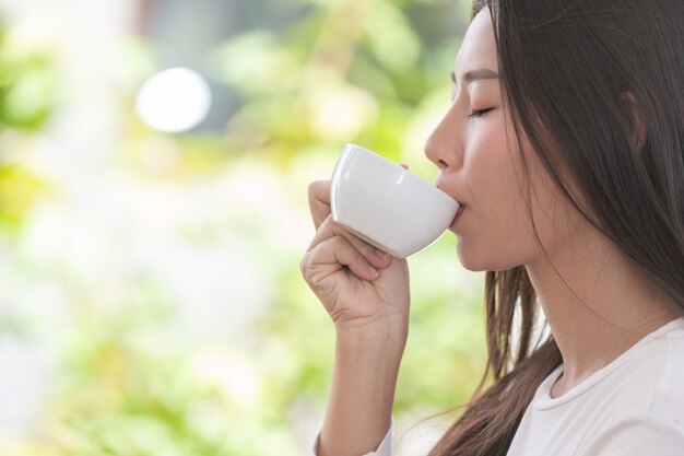 コーヒーショップに座っている長袖の白いシャツを着ている美しい女性