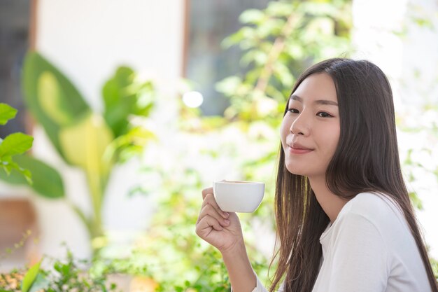 커피 숍에 앉아 긴팔 흰 셔츠를 입고 아름다운 여자