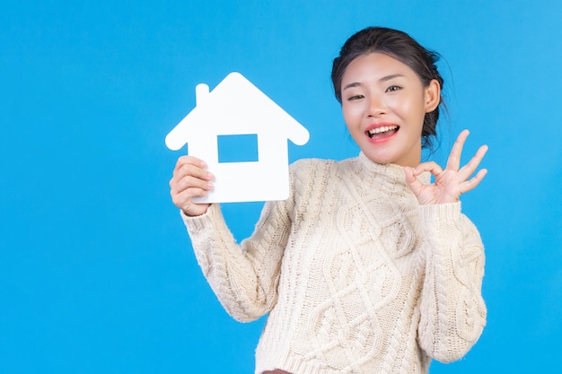 A beautiful woman wearing a new long sleeved white shirt with a house symbol  . House trading .