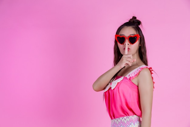 Free photo a beautiful woman wearing red glasses with a big hat on a pink .