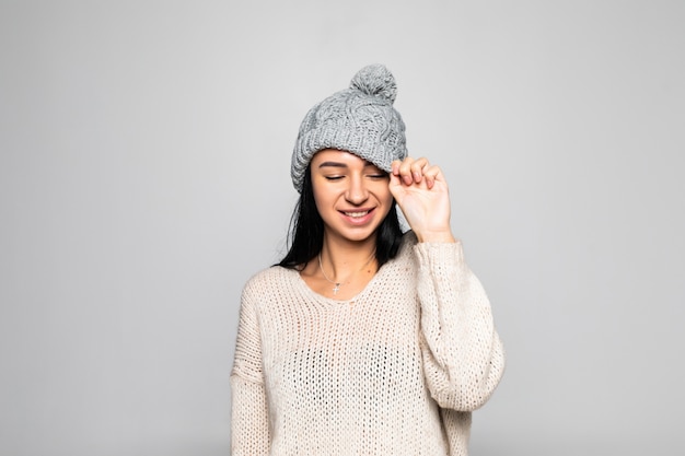 Beautiful woman wearing warm clothes, winter portrait isolated on grey wall.