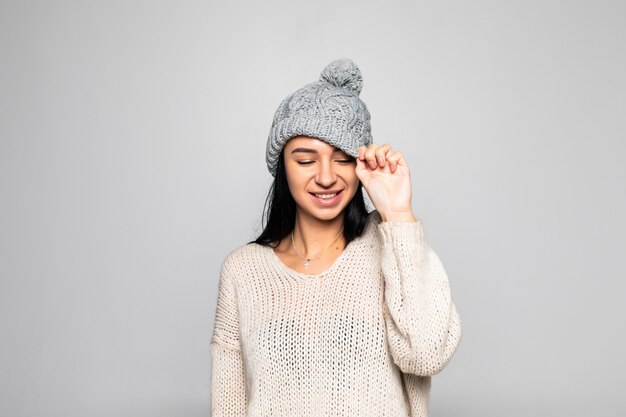 Beautiful woman wearing warm clothes, winter portrait isolated on grey wall.