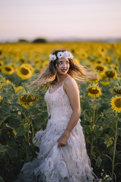 흰 드레스를 입고 해바라기 밭에 서있는 아름다운 여자