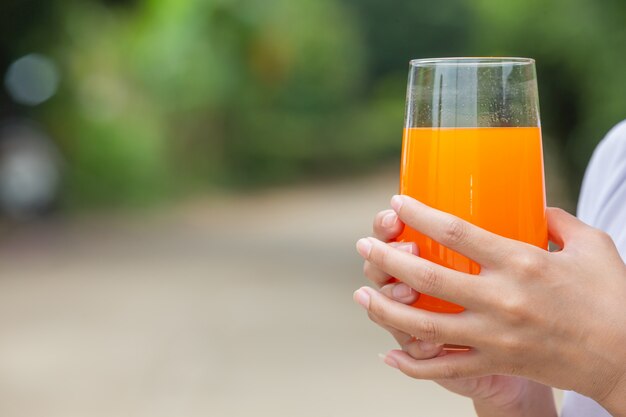 Beautiful woman wearing a white T-shirt holding a glass of orange juice