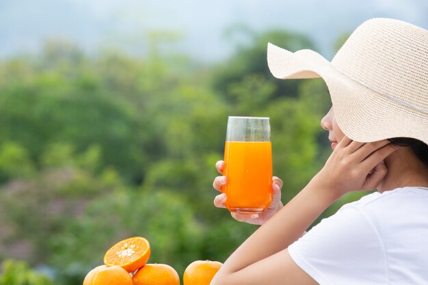 Beautiful woman wearing a white T-shirt holding a glass of orange juice