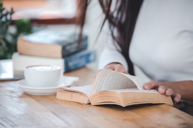 Beautiful woman wearing a white T-shirt reading a wooden table in a white room