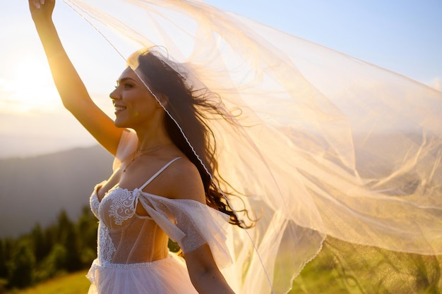 Beautiful woman in wedding dress looking at sunset in mountains