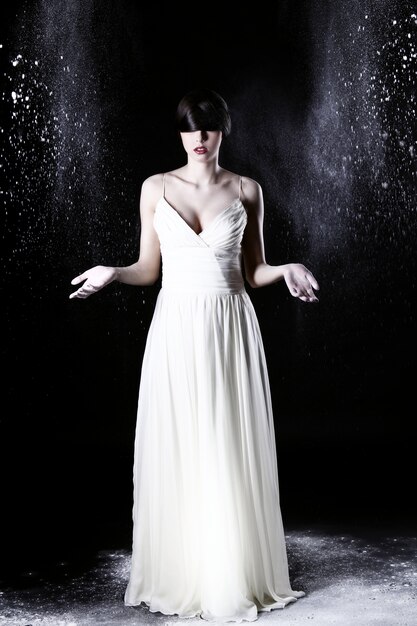 Beautiful woman in white dress and flying dust