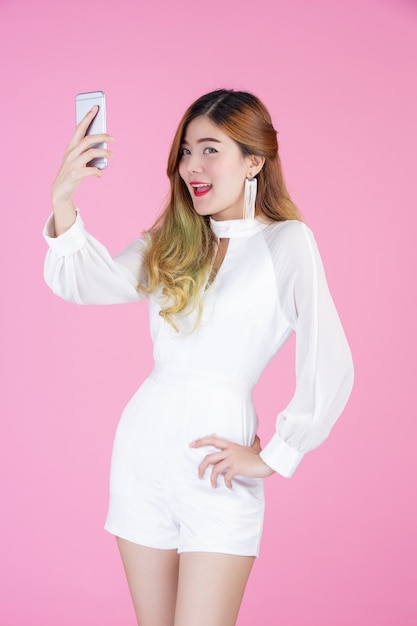 Красивая женщина, белое платье показывает телефон и настроение лица
