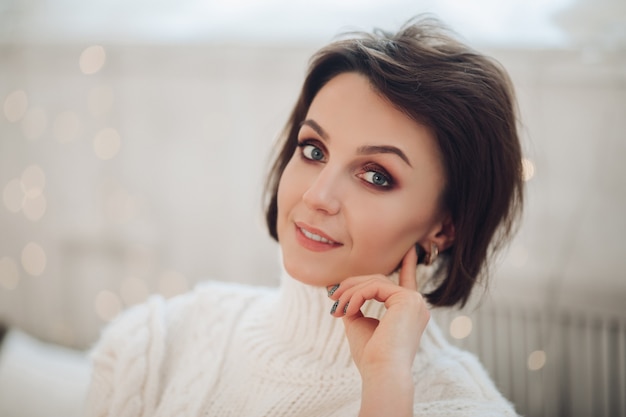 Beautiful woman in white sweater at home