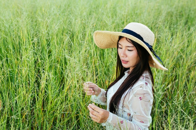 A beautiful woman who is sitting in the grassland happily.