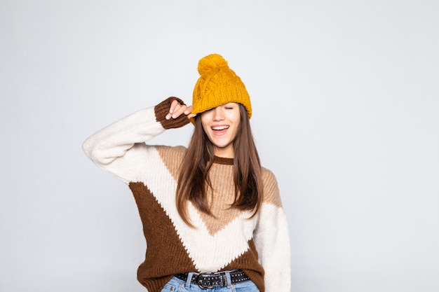 Beautiful woman winter portrait. Smiling girl wearing warm clothes having fun hat and sweater isolated on white wall