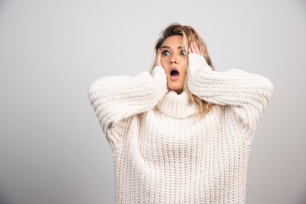 Beautiful woman in winter sweater looking surprised. 