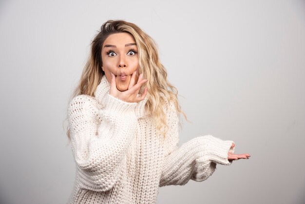 Beautiful woman in winter sweater making playful face. 