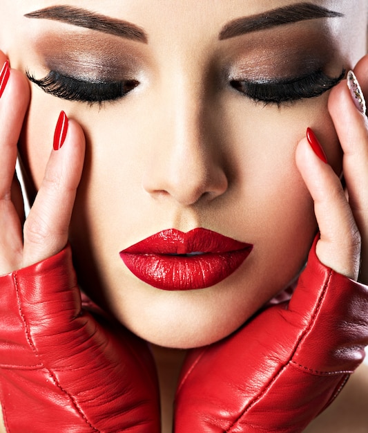 明るいファッションメイクとセクシーな唇に赤い口紅を持つ美しい女性。クローズアップの肖像画。