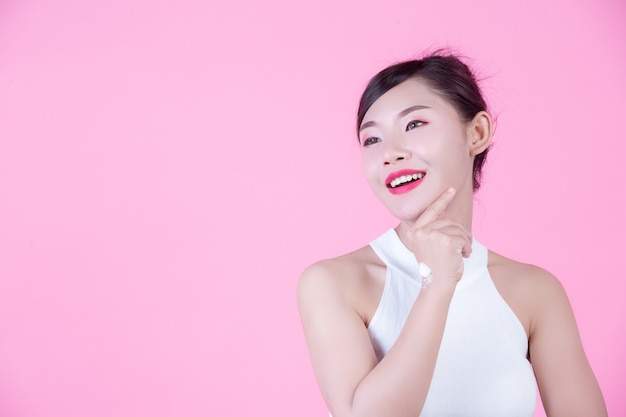 Free photo beautiful woman with cream on the skin on a pink background.